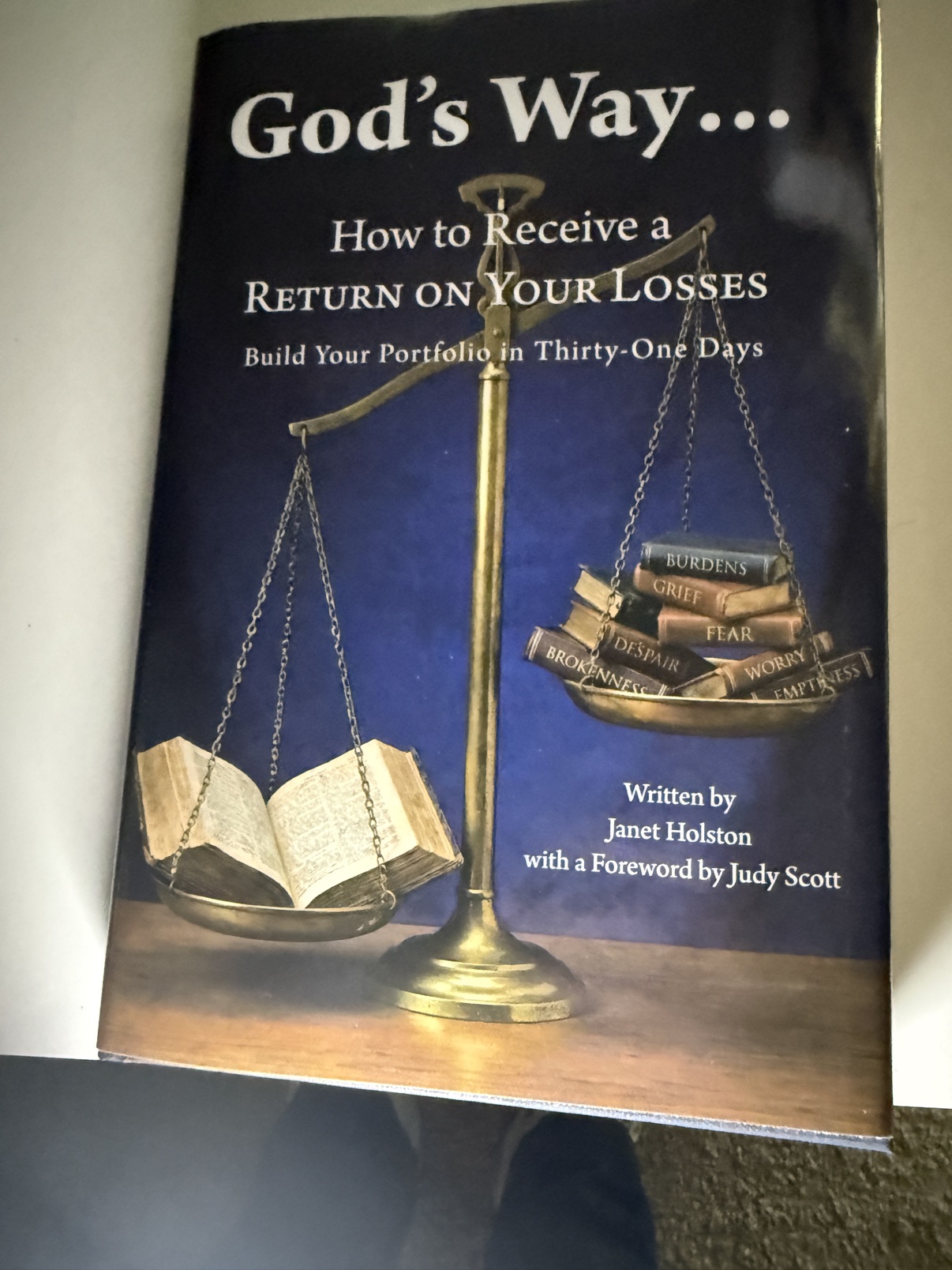 Front cover of God's Way... How to Receive a Return on Your Losses by Janet Holston — a balance scale weighing burdens, grief, fear, worry, despair, brokenness and emptiness against an open Bible
